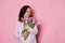 Delightful brunette, pregnant woman holding bunch of tulips on  pink background. Spring and femininity concept