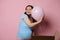 Delightful conscious pregnant woman gently hugging pink balloon, feeling happy positive emotions expecting a baby girl,