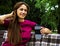 Delightful girl drinking coffee in a park sitting on a bench