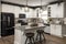 delightful and inviting kitchen space with white cabinetry, sleek black appliances, and natural stone countertops