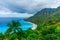 Delightful natural wild landscape with rocky mountains overgrown dense green jungle tree, palm and clear azure water of sea ocean