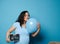 Delightful pregnant woman hugging blue balloon, posing with ultrasonography image of her future baby boy, blue backdrop