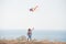 Delightful small free active boy laughing holding flying color kite near blue sea shore and sky in summer leisure