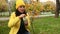 Delightful woman in yellow hat and jacket blows soap bubbles in autumn park