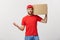 Deliver Concept: Young caucasian handsome delivery man holding a box on shoulder. Isolated over grey background.