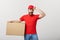 Deliver Concept: Young caucasian handsome delivery man holding a box on shoulder. over grey background.