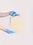 Delivery against Coronavirus 2019-nCov in pandemic Contactless delivery. Male hand in blue medical gloves holds craft paper bag on