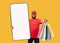 Delivery app. African american courier holding big cellphone with empty screen and stretching shopping bags, mockup