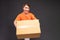 Delivery asian woman or courier wearing an orange uniform holds a cardboard box in studio