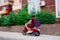 Delivery boy wearing red uniform on scooter with isothermal food case box driving fast. Express food delivery service