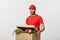 Delivery Concept: Handsome Caucasian grocery delivery courier man in red uniform with grocery box with fresh fruit and