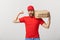 Delivery Concept - Portrait of Strong handsome delivery man flexing his muscle and holding pizza box packages. Isolated