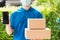 Delivery express courier young man giving boxes to customer he wears protective face mask at front home and show mobile phone