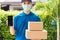 Delivery express courier young man giving boxes to customer he wears protective face mask at front home and show mobile phone