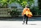 Delivery man with backpack. caucasian deliveryman isolated in orange uniform on park background. Contacless delivery service