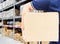 Delivery man in blue uniform holding the box on warehouse blurred Background