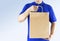 Delivery man in blue uniform and holding paper bag with delivering package on gray background. Concept fast food delivery service