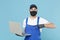 Delivery man in cap t-shirt uniform sterile mask gloves isolated on blue background studio. Guy employee courier hold