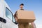 Delivery Man Carrying Cardboard Box By Truck Against Sky