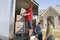 Delivery Man And Couple Unloading Moving Boxes From Truck