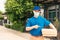 Delivery man courier sending and holding fast food pizza boxed in uniform he protective face mask pointing finger to pizza box