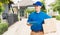 Delivery man courier in uniform hold parcel post boxes service shipment and walking finding and looking for customer home