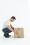 Delivery man crouching while picking cardboard box