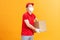 Delivery man employee in red cap blank tshirt uniform face mask glove hold empty cardboard box isolated on yellow background