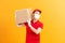 Delivery man employee in red cap blank tshirt uniform face mask glove hold empty cardboard box isolated on yellow background