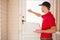 Delivery man holding pizza while knocking on the door