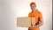 Delivery man in orange uniform delivering a big box. Light gray backround, 4K studio shot
