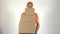Delivery man in orange uniform delivering big stack of cardboard boxes. Light gray backround, 4K studio shot
