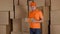 Delivery man in orange uniform delivering damaged parcel to customer. Brown cartons background. Flaw and unprofessional