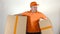 Delivery man in orange uniform delivering two big cartons. Light gray backround, 4K studio shot