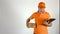 Delivery man in orange uniform giving a small parcel. Light gray backround, 4K studio shot