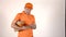 Delivery man in orange uniform using his tablet PC and giving a parcel to customer. Gray backround 4K isolated shot
