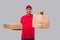 Delivery Man With Paper Bag and Three Pizza Box in Hands Isolated. Red Uniform Indian Delivery Boy. Home Food Delivery. Paper Bag