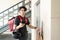 Delivery Man With Parcel Waiting For Elevator In Apartment