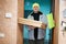 Delivery man with pizza cardboard boxes. Courier in green color hat holding a clipboard while standing against door of residential