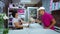 Delivery man receiving pretty wedding bouquet from happy smiling florist woman at flower shop