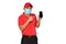 Delivery man in red uniform, medical face mask, protective gloves holding and introducing use of smart phone for delivery