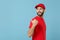 Delivery man in red uniform workwear isolated on blue wall background, studio portrait. Professional male employee in