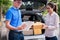 Delivery man signing checklist of delivery package box to happy