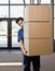 Delivery man in uniform carrying stack of boxes