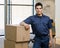 Delivery man in uniform posing with stack of boxes