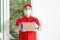 A delivery man wearing a red dress holds a parcel box