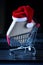 Delivery package with santa hat in grocery cart on laptop in background. Online shopping, Christmas and holidays giving away,