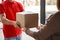 Delivery of parcel from courier to client. Deliveryman in red uniform gives box to girl