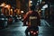 Delivery person on motorcycle carries large yellow package in busy city at night