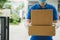 Delivery service man in blue uniform waiting for sending parcel post box to customer at door home